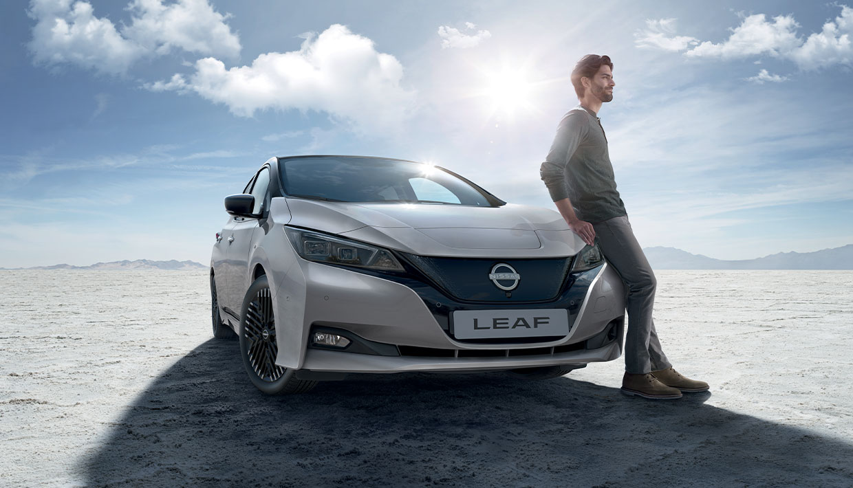 Homme assis sur l'aile gauche de la Nissan Leaf